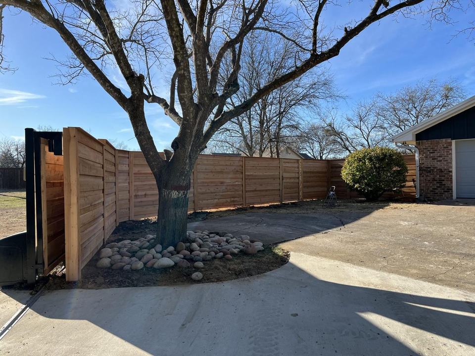 Horizontal cedar privacy fence with cap and trim around a tree in Midlothian, TX