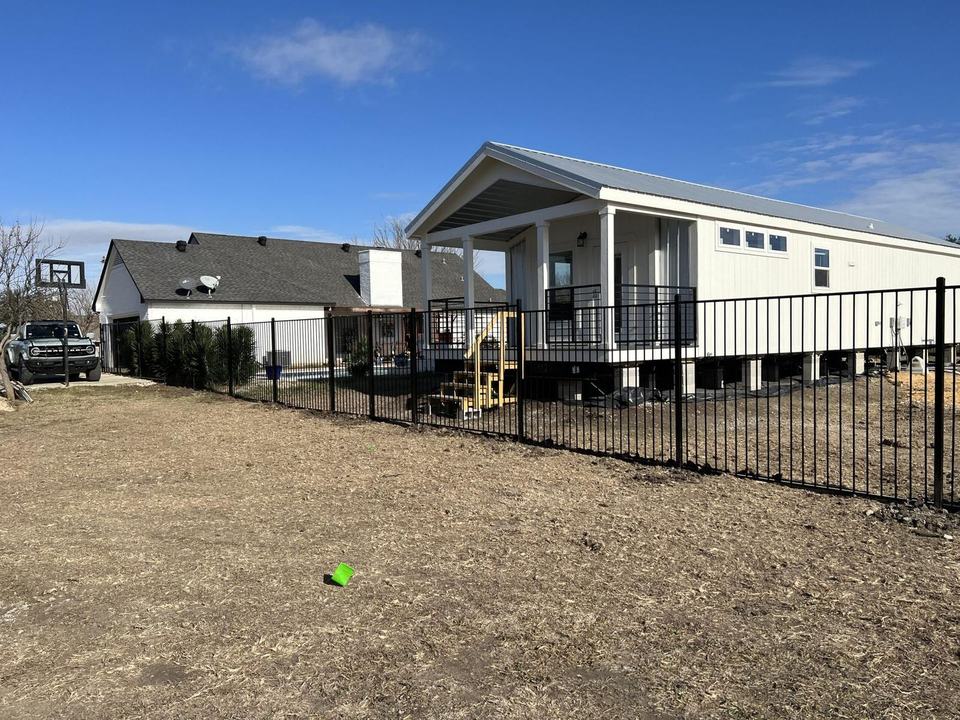 Six foot flat-top iron fence around a backyard