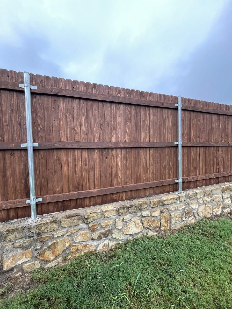 Stained cedar fence on a stone retaining wall