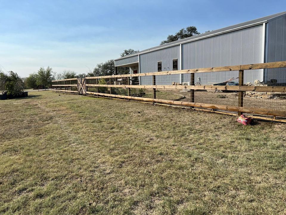 Three-rail wood ranch fence with hog panel